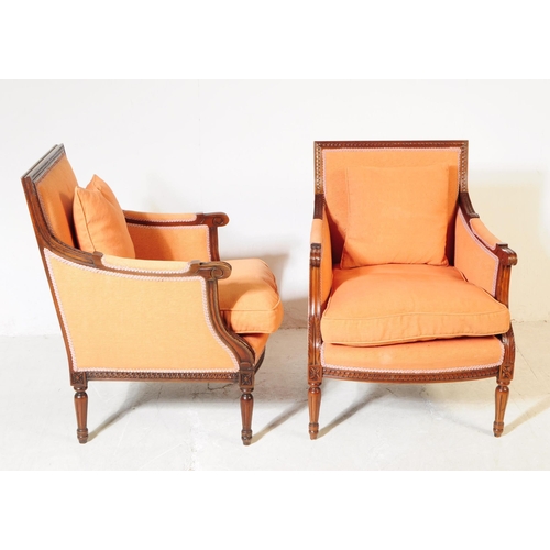 1055 - A pair of 20th century bergere French armchairs. The chairs having mahogany frames with moulded deta... 