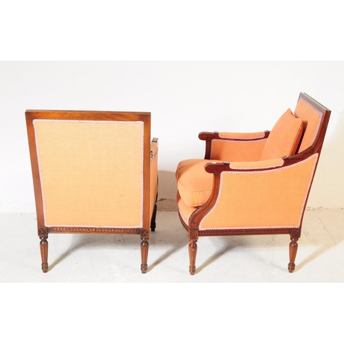 1055 - A pair of 20th century bergere French armchairs. The chairs having mahogany frames with moulded deta... 