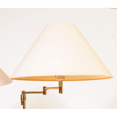 1088 - Two 20th century brass adjustable swing arm floor standing standard lamps. The lamps each raised on ... 