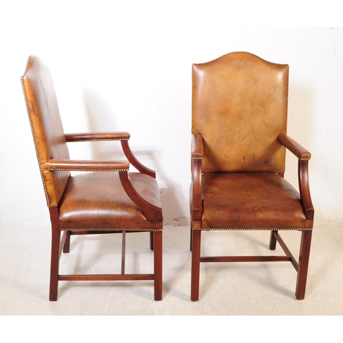 1106 - A pair of 20th century George III style leather and mahogany Gainsborough chairs having leather upho... 