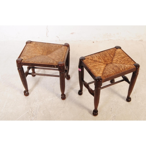 1122 - A pair of early 20th century oak wood rush seat stools. The stools raised on tapered rounded legs ov... 