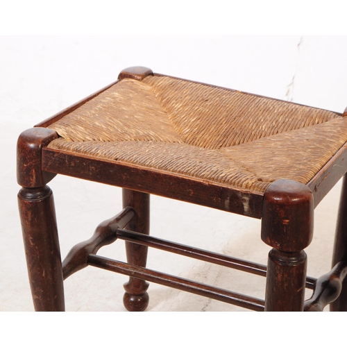 1122 - A pair of early 20th century oak wood rush seat stools. The stools raised on tapered rounded legs ov... 