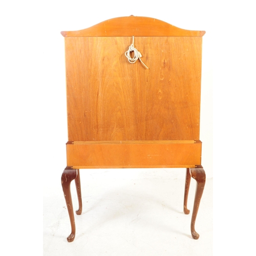 1125 - A 20th century walnut cocktail cabinet. The cabinet raised on carved cabriole legs, having a pair of... 