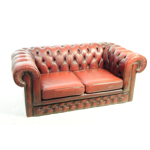 1126 - A 20th century Chesterfield two seater sofa settee. The sofa in oxblood red leather, featuring a but... 