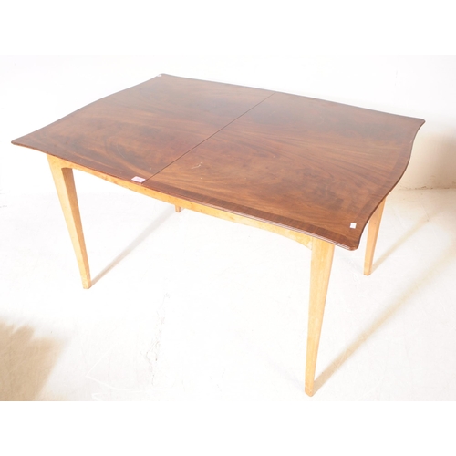 568 - A mid 20th century walnut veneer extending dining table. The table having armorial shaped top, raise... 