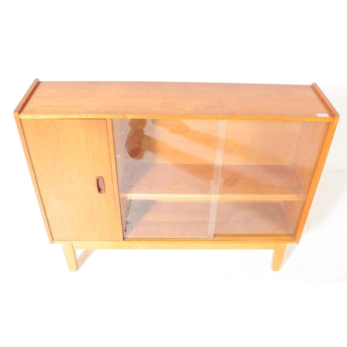 647 - British Modern Design - A mid 20th century teak glazed bookcase cabinet. The bookcase featuring a cu... 