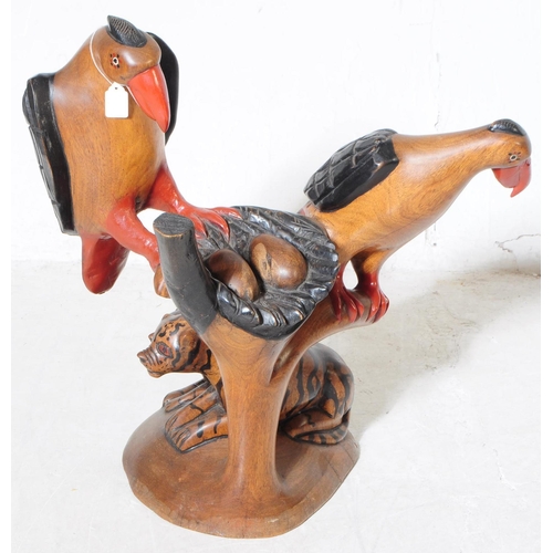 701 - Two 20th century carved wooden bird sculptures. The larger of the two in the form of two vultures wi... 