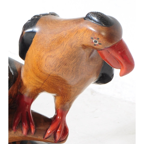 701 - Two 20th century carved wooden bird sculptures. The larger of the two in the form of two vultures wi... 