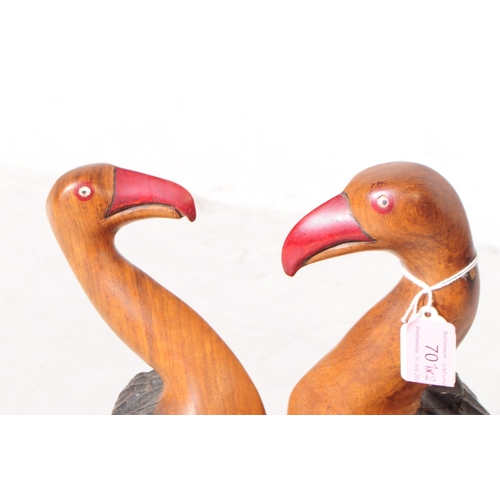 701 - Two 20th century carved wooden bird sculptures. The larger of the two in the form of two vultures wi... 