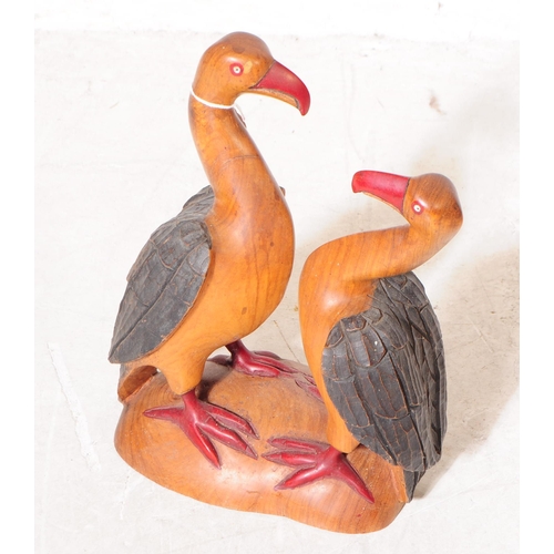 701 - Two 20th century carved wooden bird sculptures. The larger of the two in the form of two vultures wi... 