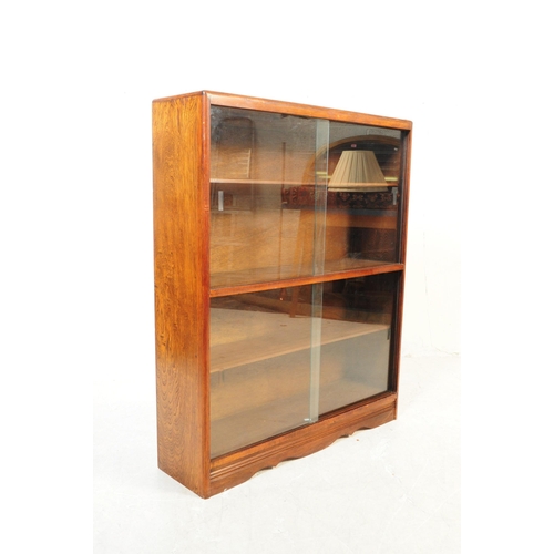 716 - British Modern Design - A mid 20th century oak glazed display cabinet having twin glazed doors openi... 