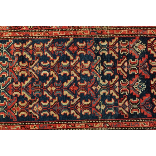 892 - A 20th century Persian runner carpet rug. The rug having a dark blue central field populated with po... 