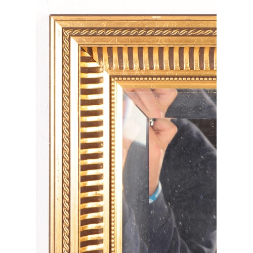 941 - A large contemporary gilt framed overmantle wall mirror. The mirror of rectangular form, with centra... 