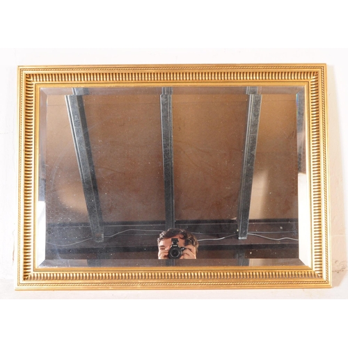 941 - A large contemporary gilt framed overmantle wall mirror. The mirror of rectangular form, with centra... 