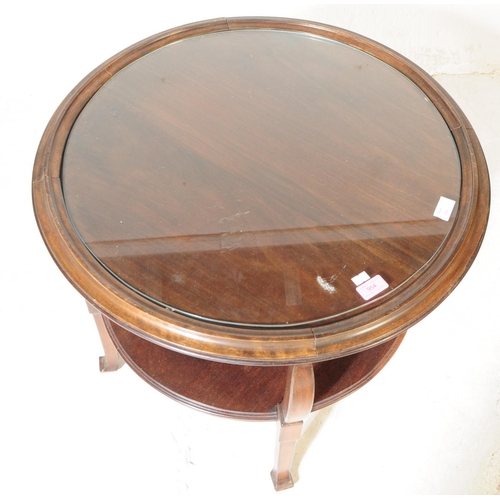 954 - An early 20th century oak wood round two tier coffee table. The coffee table having an inset circula... 