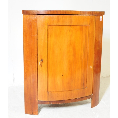 961 - A 19th century Biedermeier corner cabinet. The cabinet raised on stile legs, having a bow fronted do... 