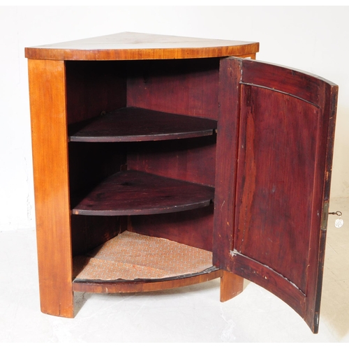 961 - A 19th century Biedermeier corner cabinet. The cabinet raised on stile legs, having a bow fronted do... 