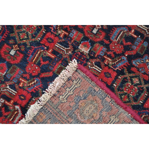 1037 - A late 19th century Persian Iranian Hamadan carpet floor rug. The rug having a red ground with black... 