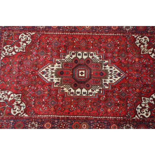 1042 - A mid 20th century Persian Goltuk hand knotted carpet floor rug. The rug having a red ground with la... 