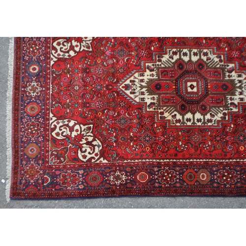 1042 - A mid 20th century Persian Goltuk hand knotted carpet floor rug. The rug having a red ground with la... 