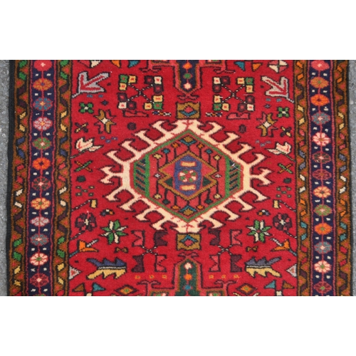 982 - A 20th century North West Persian Heriz runner carpet floor rug. Having a red central field populate... 