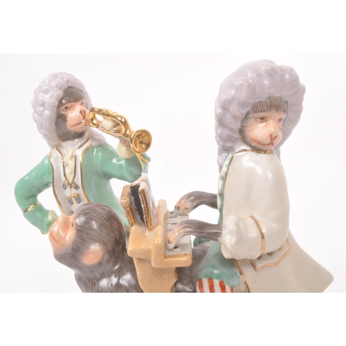 47 - Two 20th century Meissen manner porcelain monkey figures. One figure depicting a monkey stood, with ... 