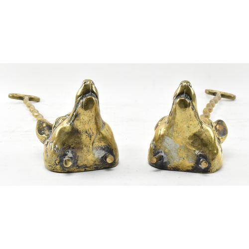 259 - A pair of Victorian 19th century brass fox head door stops. Each with a handle atop over a central b... 