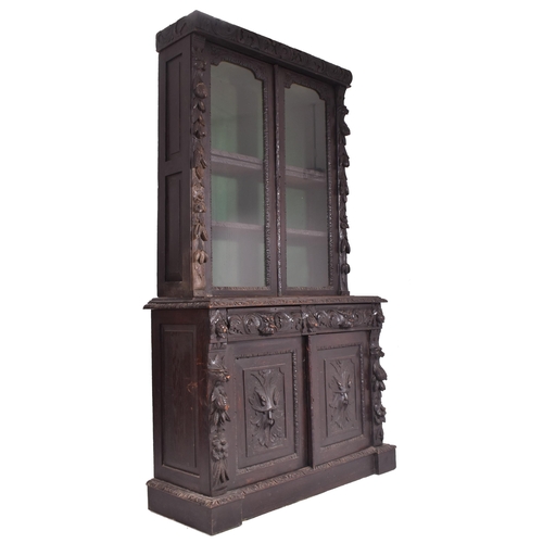 292 - A Victorian 19th century carved oak library bookcase. The cabinet top having two glazed doors flanke... 