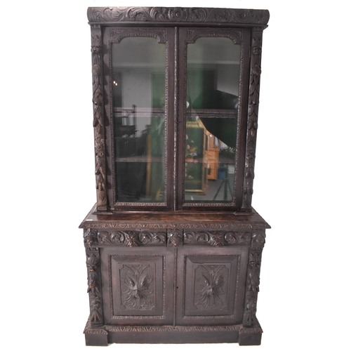 292 - A Victorian 19th century carved oak library bookcase. The cabinet top having two glazed doors flanke... 