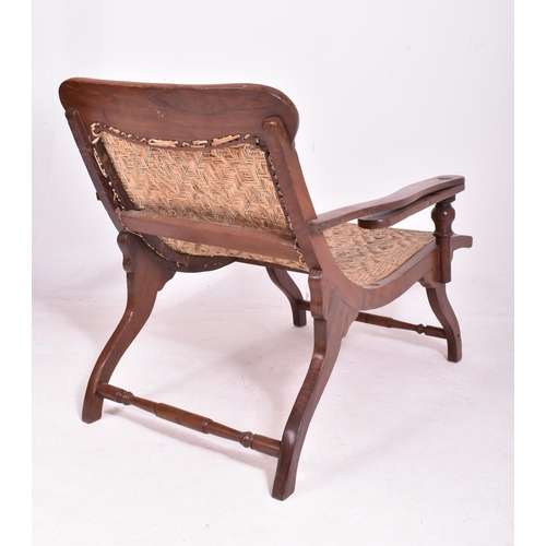 415 - An early 20th century plantation teak & wicker rattan seat lounge chair. The chair having a reclined... 