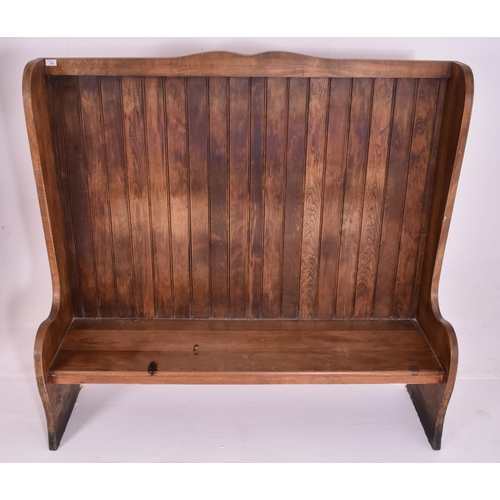 458 - A large 20th century pine hall settle bench settee bench. The hall settle having a high back with ca... 