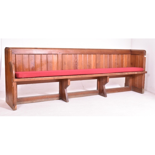 498 - An early 20th century pine ecclesiastic church pew settle bench. The bench having a panelled back wi... 