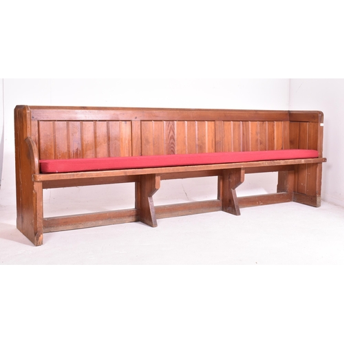 498 - An early 20th century pine ecclesiastic church pew settle bench. The bench having a panelled back wi... 