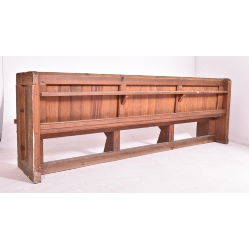 498 - An early 20th century pine ecclesiastic church pew settle bench. The bench having a panelled back wi... 