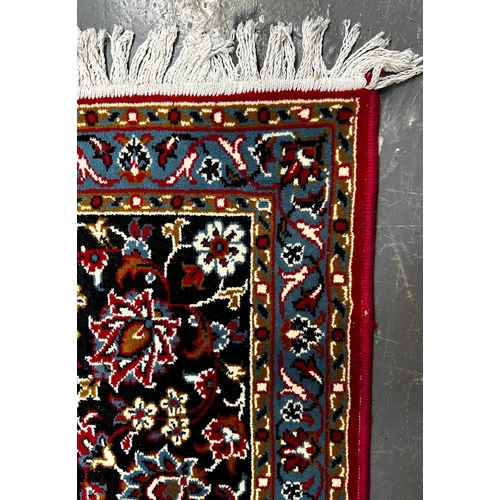 561 - A large 20th century Iranian Islamic floor carpet rug. The rug having a red panel with floral shaped... 