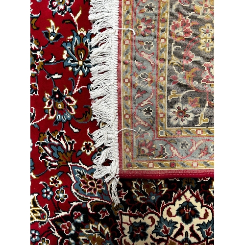 561 - A large 20th century Iranian Islamic floor carpet rug. The rug having a red panel with floral shaped... 