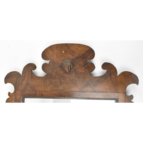 566 - An 18th century George III walnut pier mirror. The mirror having crested top over classical mask fac... 