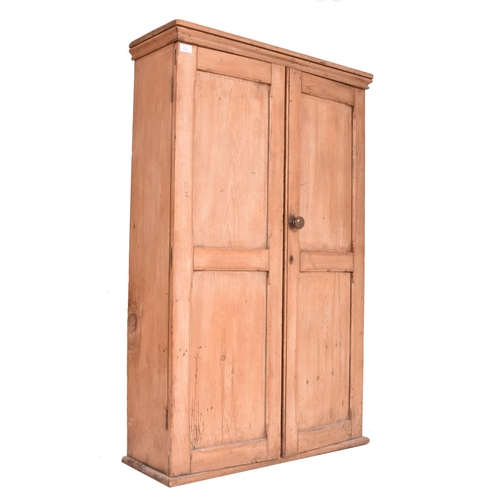 622 - An early 20th century pine wall mounted school cupboard. The cupboard having a pediment top over dou... 