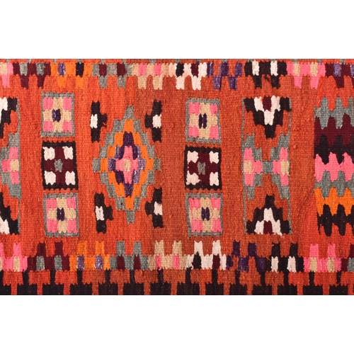 624 - A 20th century Kilim Turkish floor carpet / rug runner. The rug featuring red ground with polychrome... 