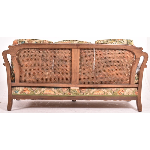 640 - An early 20th century three piece mahogany and double caned bergere suite. The suite comprising a th... 