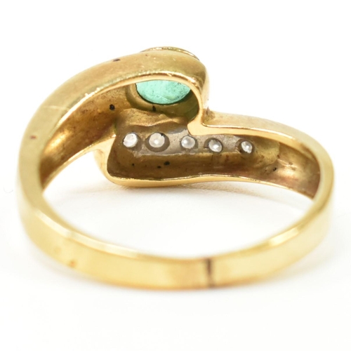 43 - A hallmarked Italian 18ct gold, diamond and emerald cross over ring. The ring having a central bezel... 