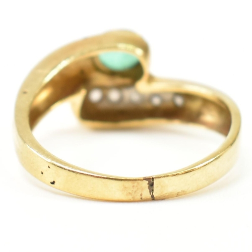 43 - A hallmarked Italian 18ct gold, diamond and emerald cross over ring. The ring having a central bezel... 