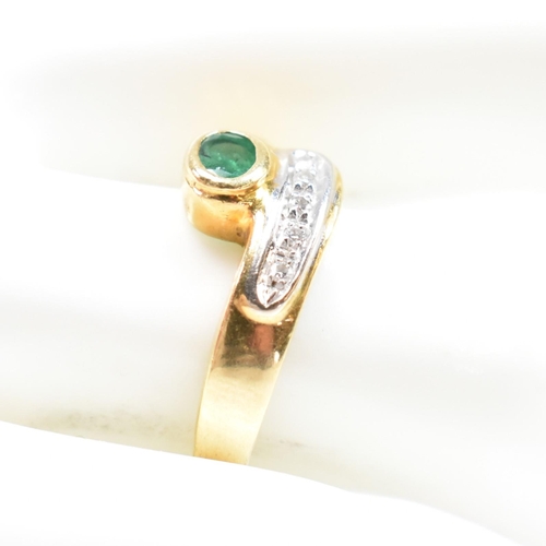 43 - A hallmarked Italian 18ct gold, diamond and emerald cross over ring. The ring having a central bezel... 