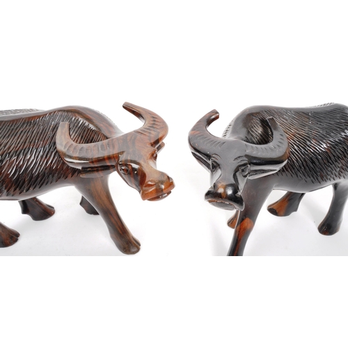 200 - A pair of 20th Century carved hardwood figures in the form of water buffalos. Both standing with hea... 