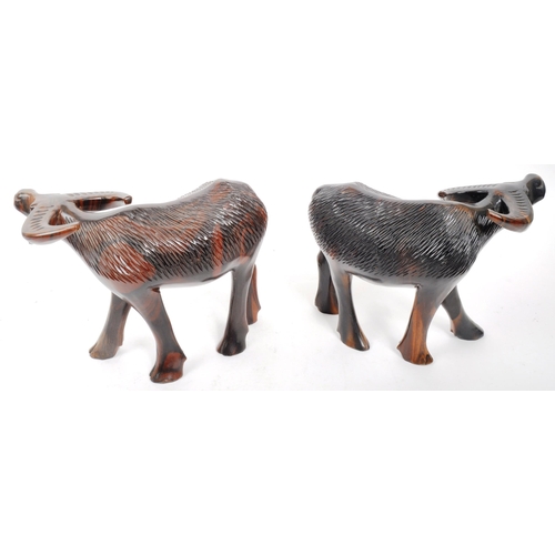 200 - A pair of 20th Century carved hardwood figures in the form of water buffalos. Both standing with hea... 