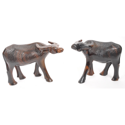 200 - A pair of 20th Century carved hardwood figures in the form of water buffalos. Both standing with hea... 