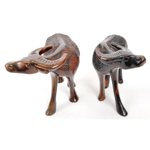 200 - A pair of 20th Century carved hardwood figures in the form of water buffalos. Both standing with hea... 