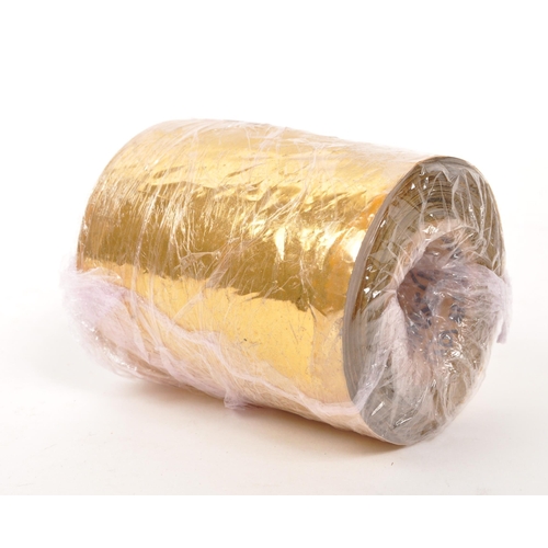 219 - A 22/24ct gold leaf roll. The roll having central cardboard tube with plastic backed gold leaf. Weig... 