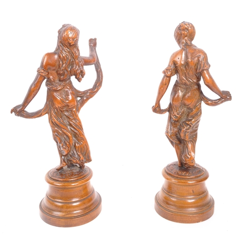 271 - A pair of bronze figurines in the form of ladies with draped clothing raised upon turned circular ba... 