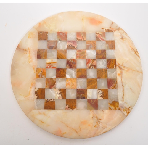 300 - A 20th Century marble circular chess board with central inlaid square board. In cream and red colour... 